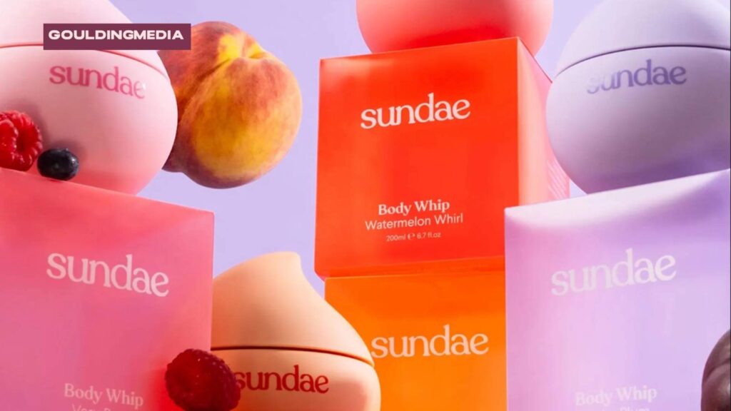 Brightly coloured Sundae body care products displayed with assorted fruits in the background.