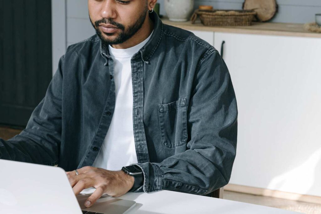 A man working on a laptop at a desk, focused on data entry or content creation.
