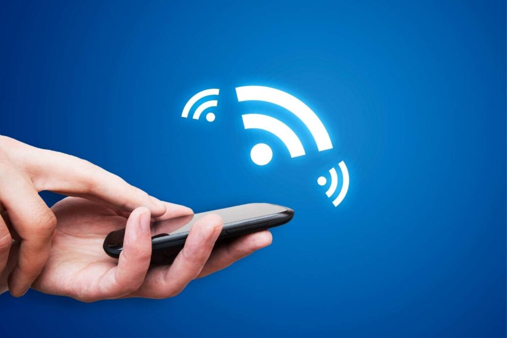 A person’s hand holding a smartphone against a blue background with a wireless NFC icon.